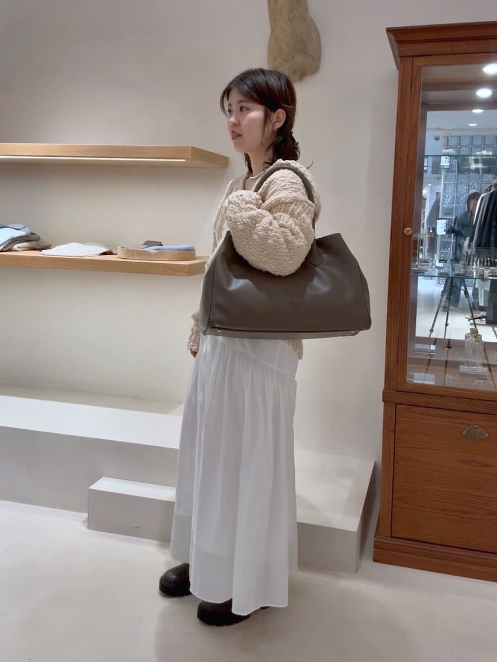 ベージュ系のニット/セーター、ホワイト系のスカート、グレー系のトートバッグを着用したレディースの冬コーディネートの4枚目の写真