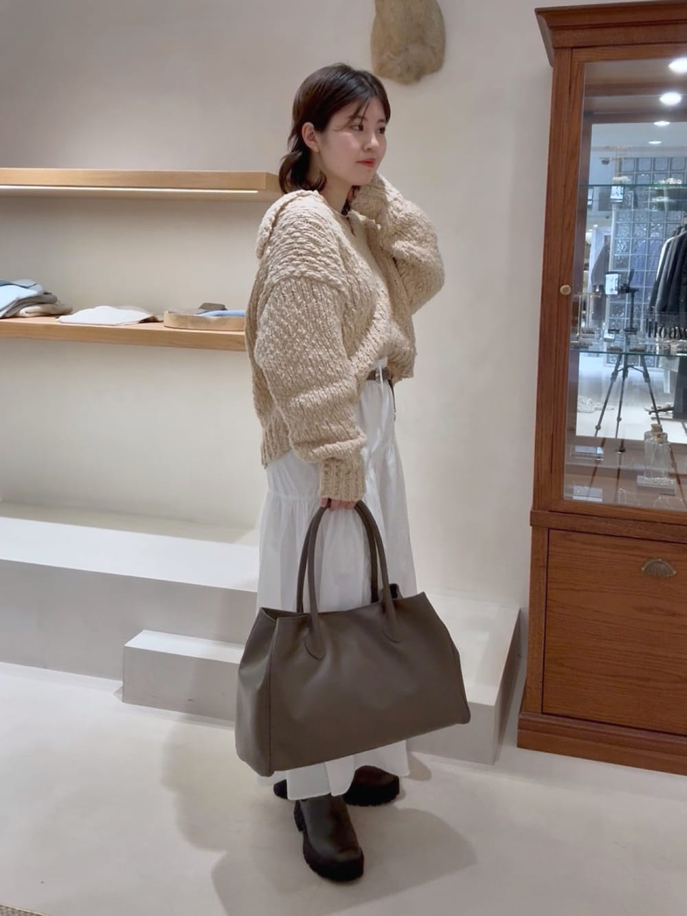 ベージュ系のニット/セーター、ホワイト系のスカート、グレー系のトートバッグを着用したレディースの冬コーディネートの3枚目の写真