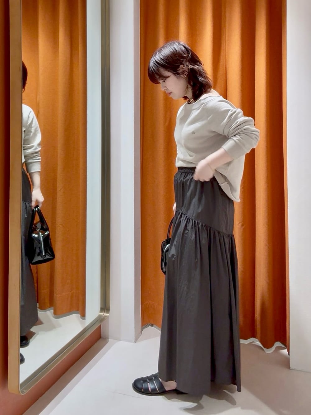 ブラウン系のスカート、ブラック系のボストンバッグ、ベージュ系のスウェットを着用したレディースの春コーディネートの5枚目の写真