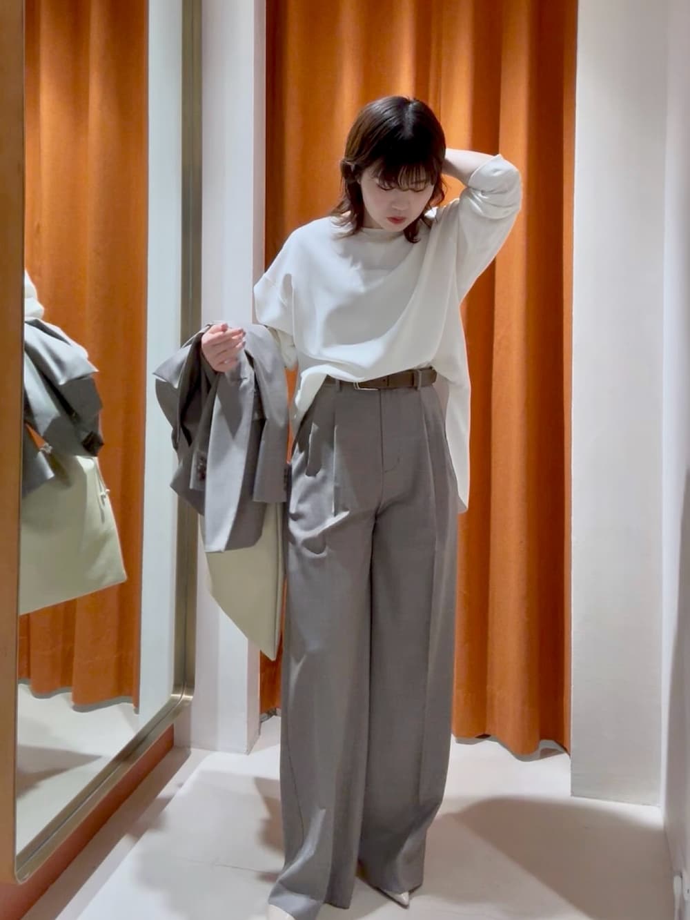 ホワイト系のシャツ/ブラウス、ブラウン系のスラックス、ホワイト系のショルダーバッグを着用したレディースの春コーディネートの3枚目の写真