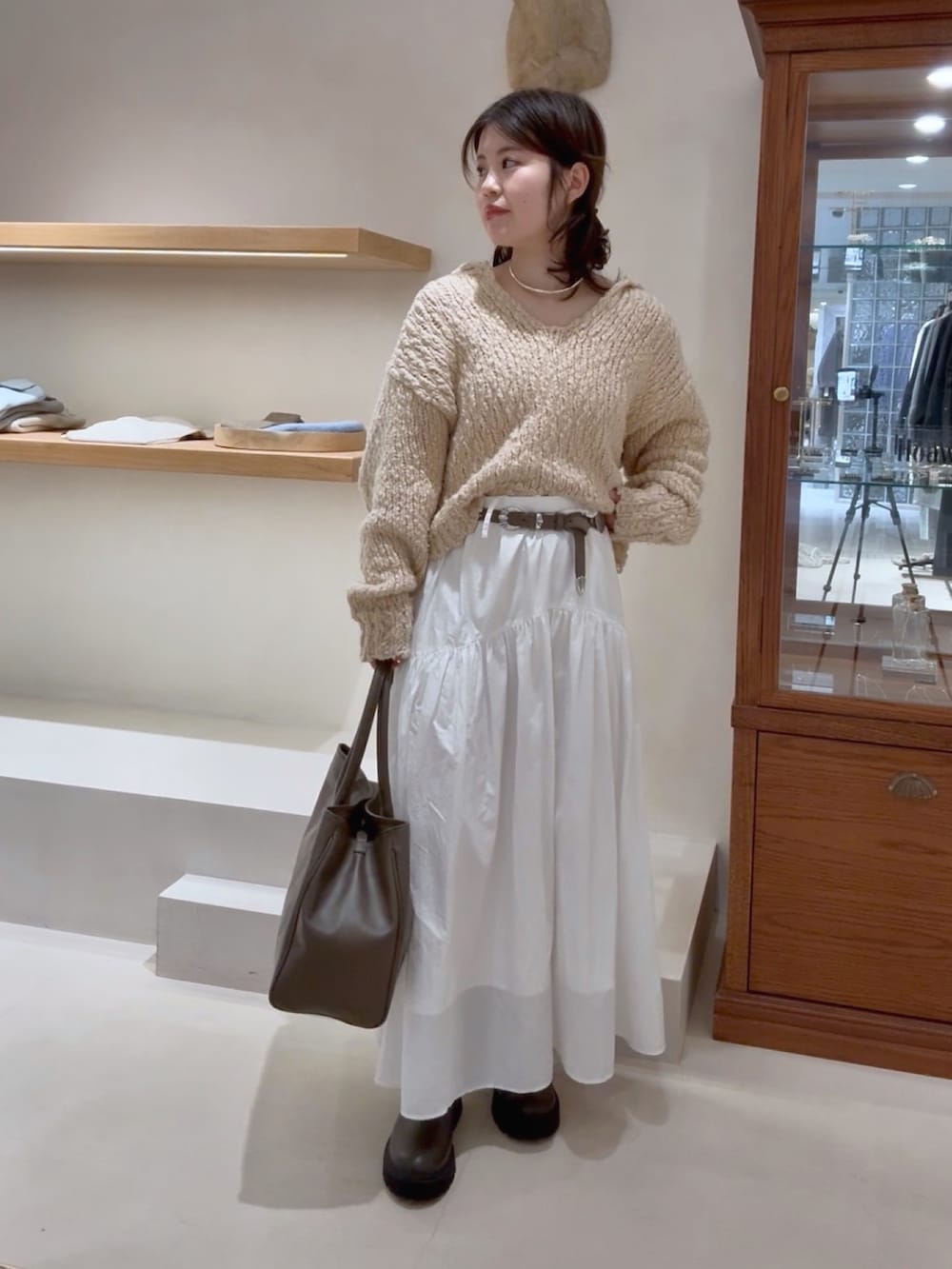 ベージュ系のニット/セーター、ホワイト系のスカート、グレー系のトートバッグを着用したレディースの冬コーディネートの2枚目の写真