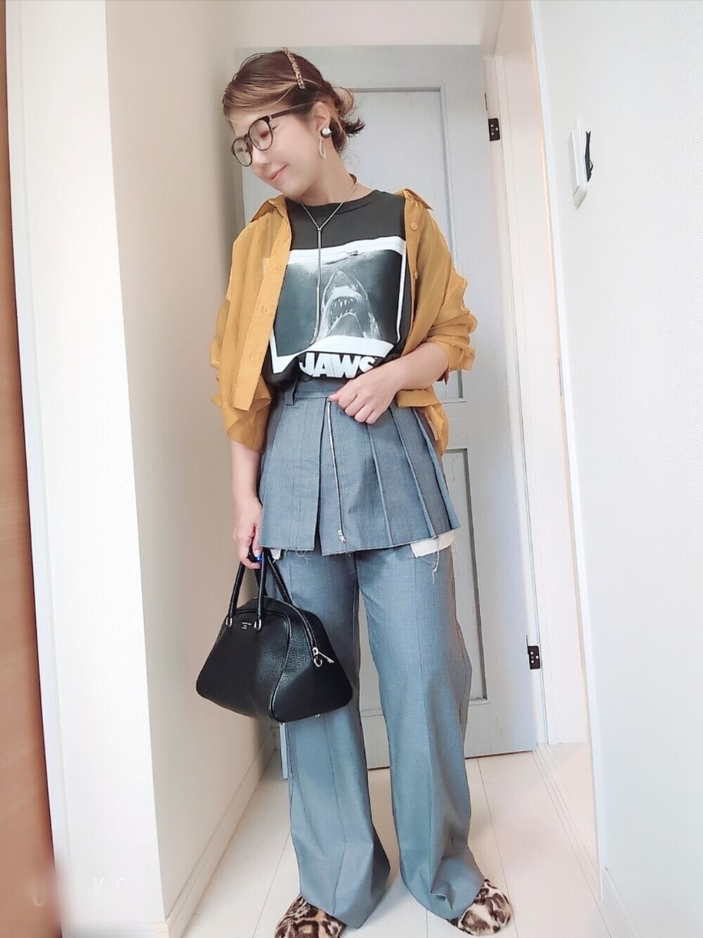 ブラック系のTシャツ/カットソー、イエロー系のシャツ/ブラウス、グレー系のスラックスを着用したレディースの秋コーディネートの2枚目の写真