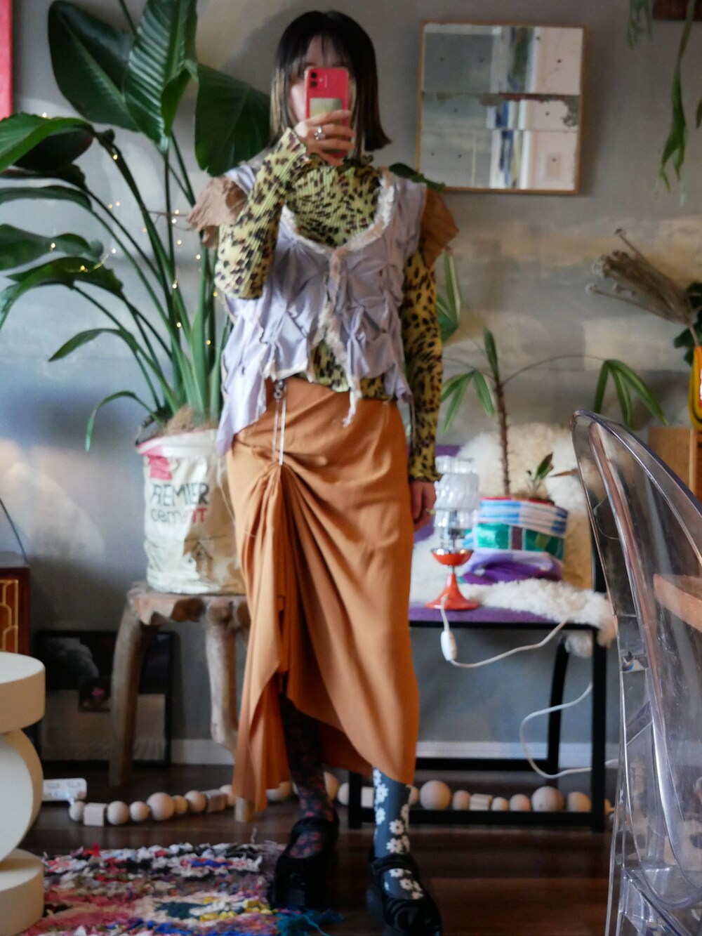 オレンジ系のスカート、ブラック系のカーディガン/ボレロ、グリーン系のTシャツ/カットソーを着用したレディースの冬コーディネートの2枚目の写真