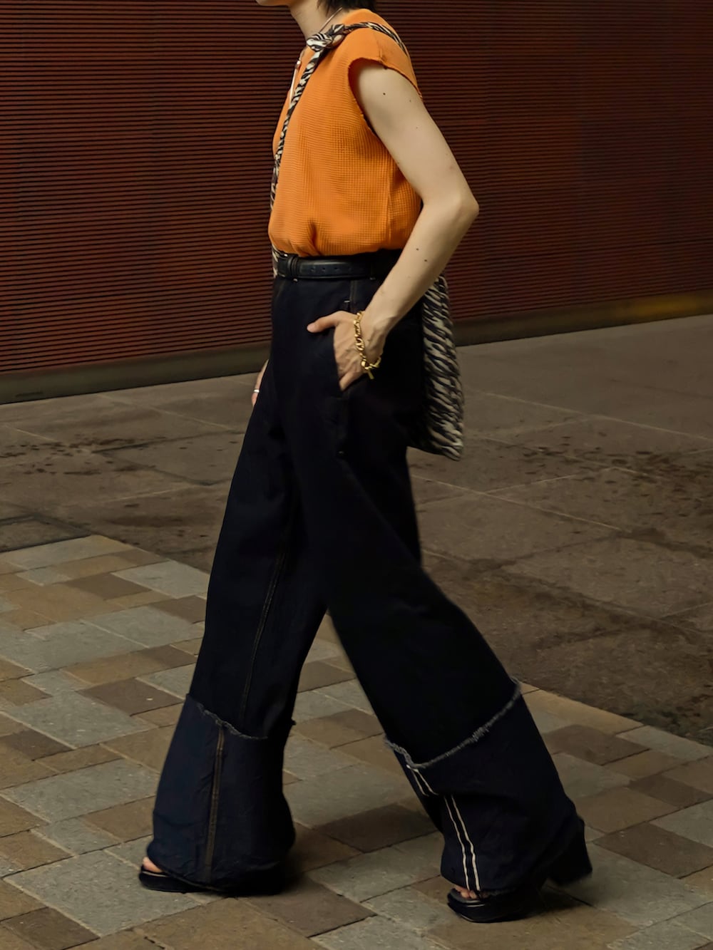 オレンジ系のTシャツ/カットソー、ブラウン系のショルダーバッグ、ブラック系のデニムパンツを着用したメンズの夏コーディネートの2枚目の写真