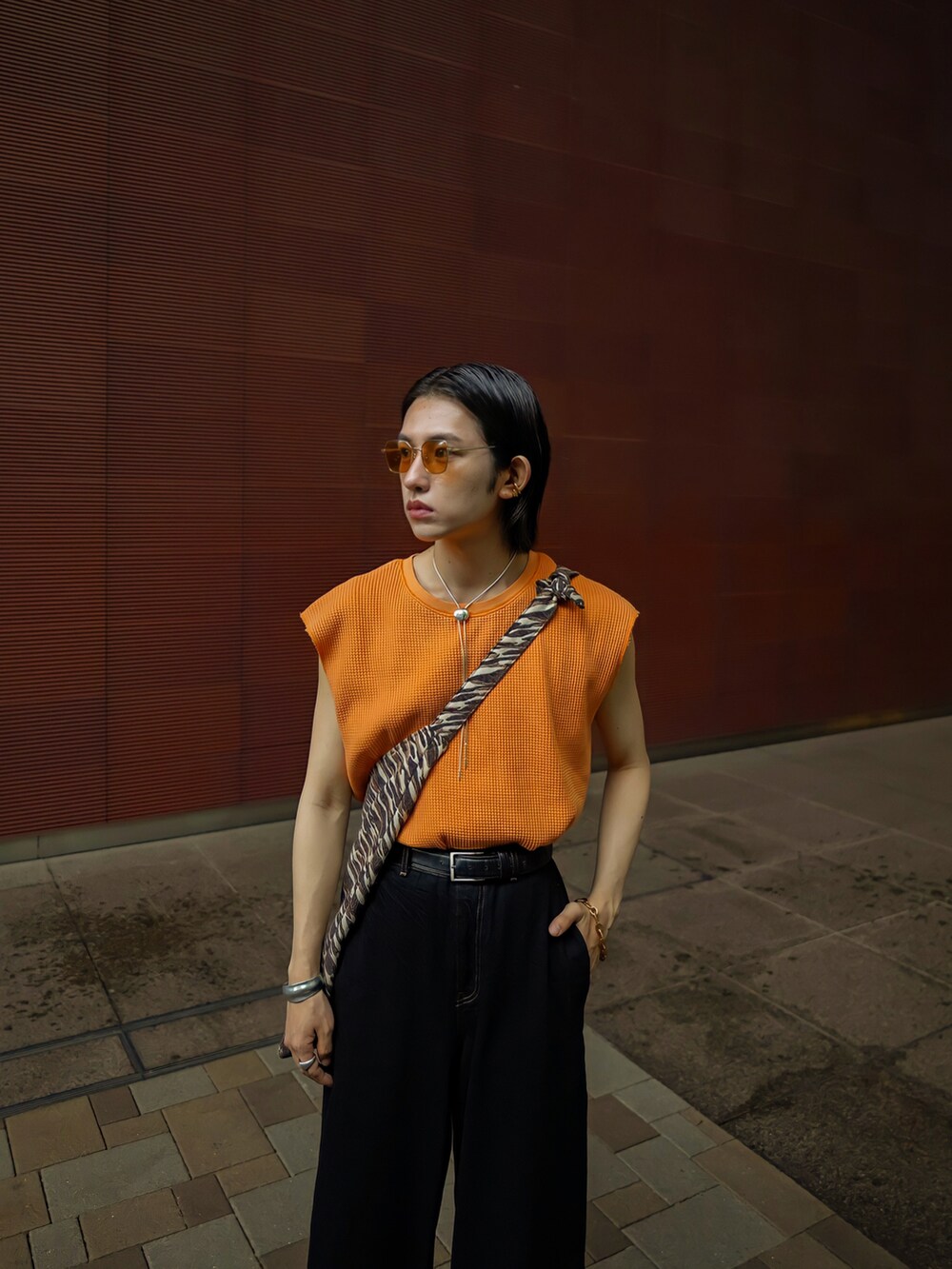 オレンジ系のTシャツ/カットソー、ブラウン系のショルダーバッグ、ブラック系のデニムパンツを着用したメンズの夏コーディネートの5枚目の写真