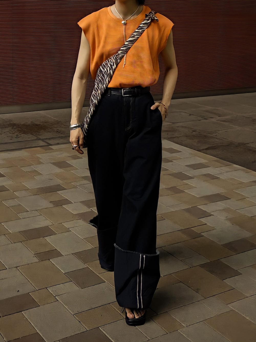 オレンジ系のTシャツ/カットソー、ブラウン系のショルダーバッグ、ブラック系のデニムパンツを着用したメンズの夏コーディネートの4枚目の写真