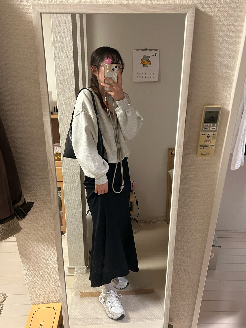 ホワイト系のその他アウター、ブラック系のハンドバッグ、ブラック系のスカートを着用したレディースの冬コーディネートの2枚目の写真