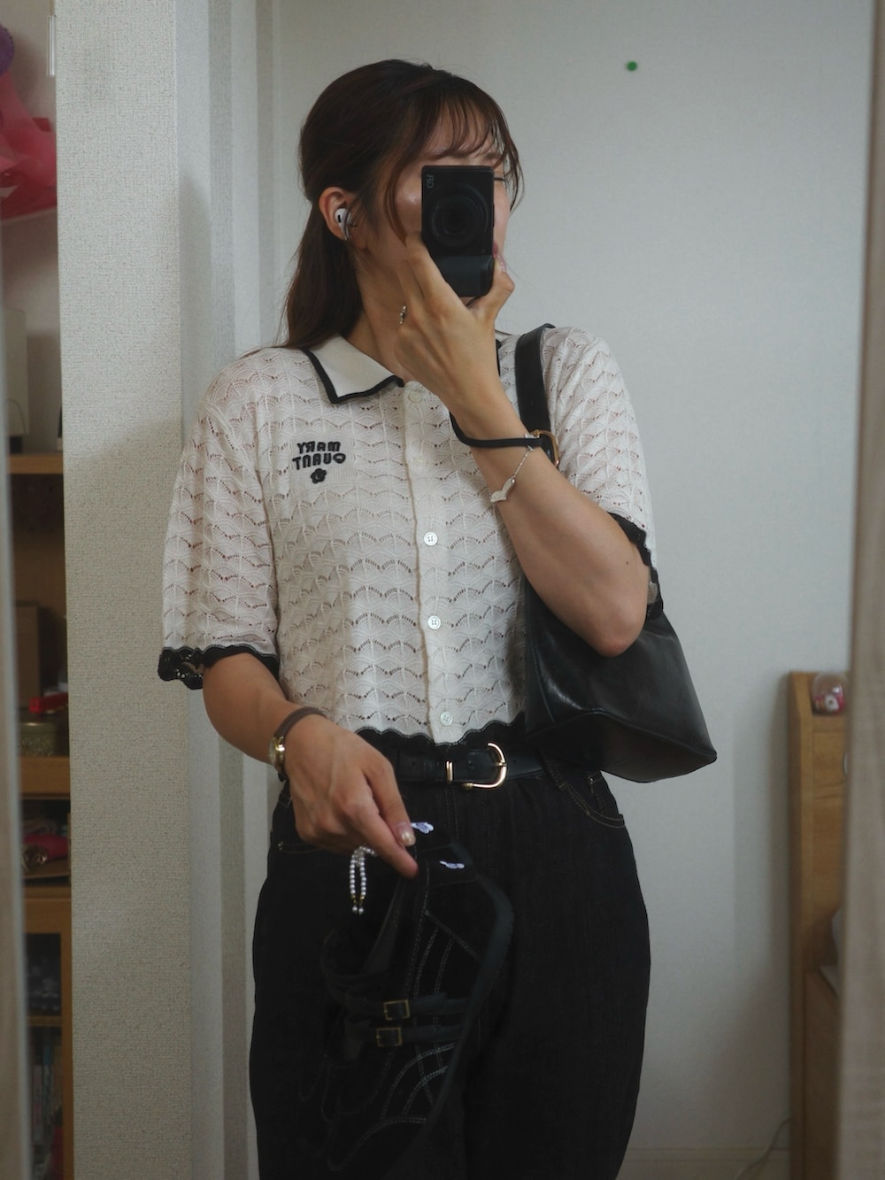 ホワイト系のカーディガン/ボレロ、ブラック系のデニムパンツ、ブラック系のハンドバッグを着用したレディースの夏コーディネートの2枚目の写真