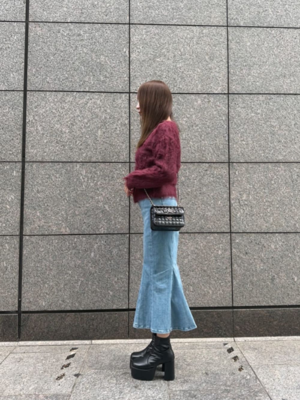 ブルー系のデニムスカート、レッド系のカーディガン/ボレロ、ブラック系のショルダーバッグを着用したレディースの冬コーディネートの3枚目の写真