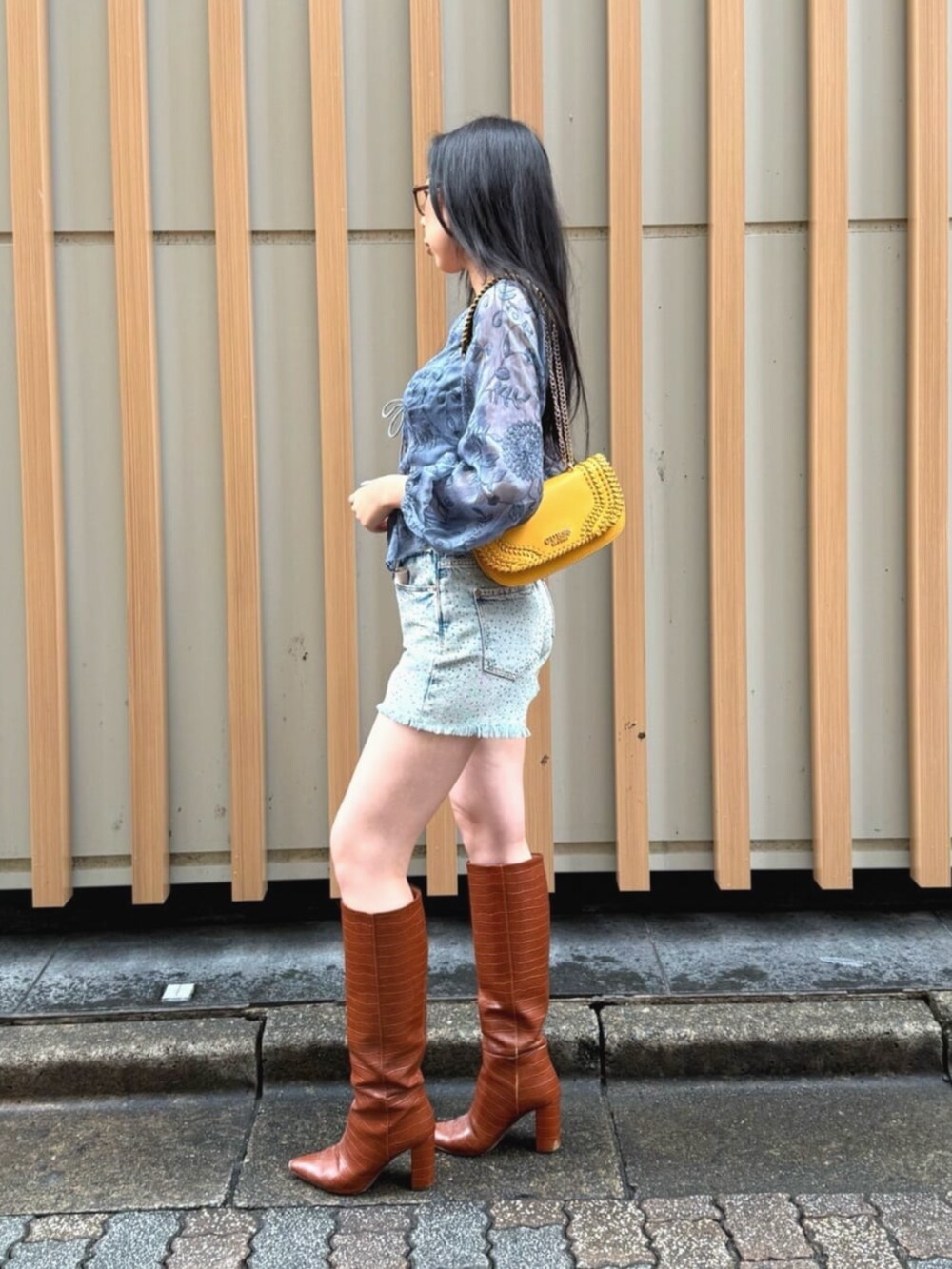 ブルー系のデニムパンツ、ブルー系のシャツ/ブラウス、オレンジ系のショルダーバッグを着用したレディースの秋コーディネートの3枚目の写真