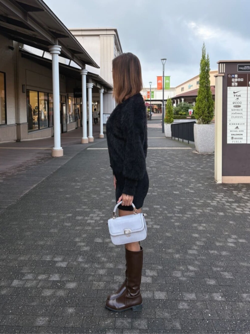 ブラック系のワンピース、パープル系のショルダーバッグを着用したレディースの秋コーディネートの3枚目の写真