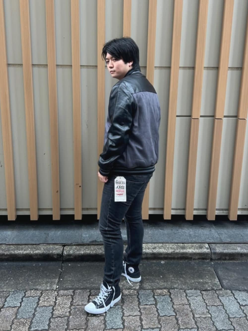 ベージュ系のTシャツ/カットソー、グレー系のスタジャン、グレー系のデニムパンツを着用したメンズの秋コーディネートの2枚目の写真