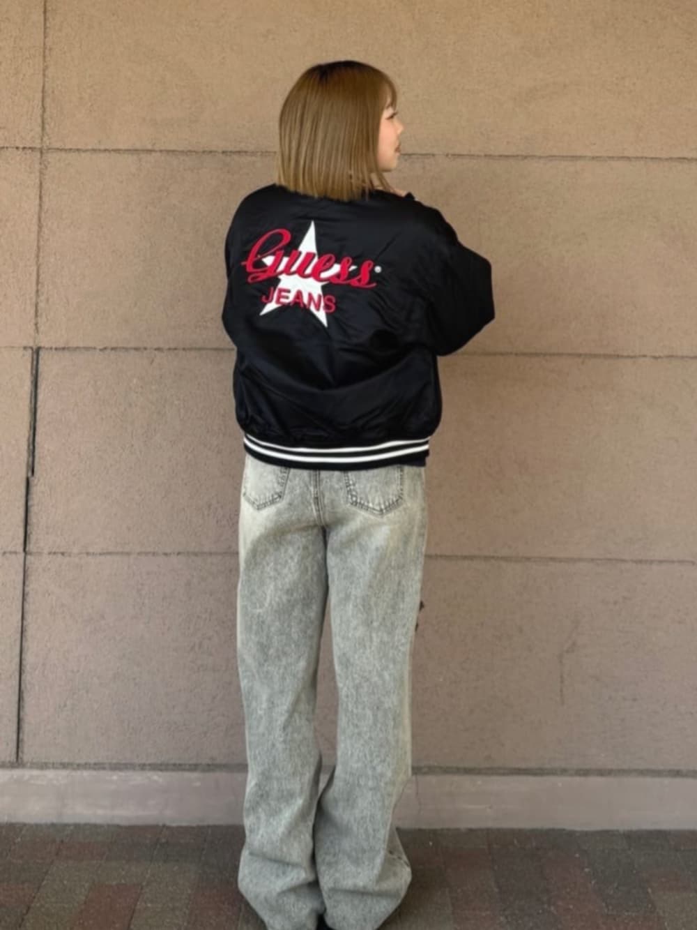 グレー系のデニムパンツ、ブラック系のスタジャン、ブルー系のスウェットを着用したレディースの冬コーディネートの2枚目の写真