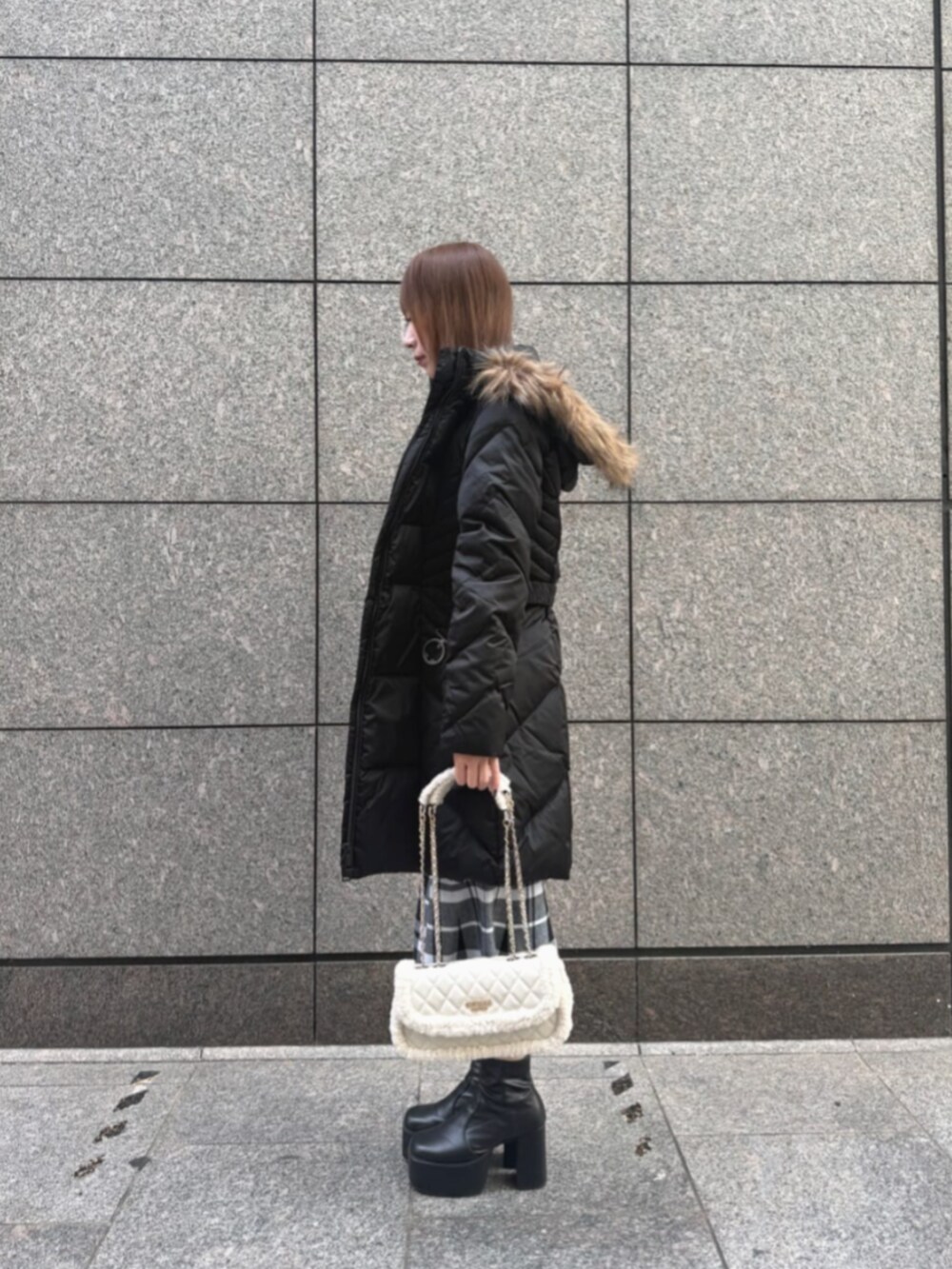 ブラック系のダウンジャケット/コート、ホワイト系のショルダーバッグ、ブラック系のワンピースを着用したレディースの冬コーディネートの2枚目の写真
