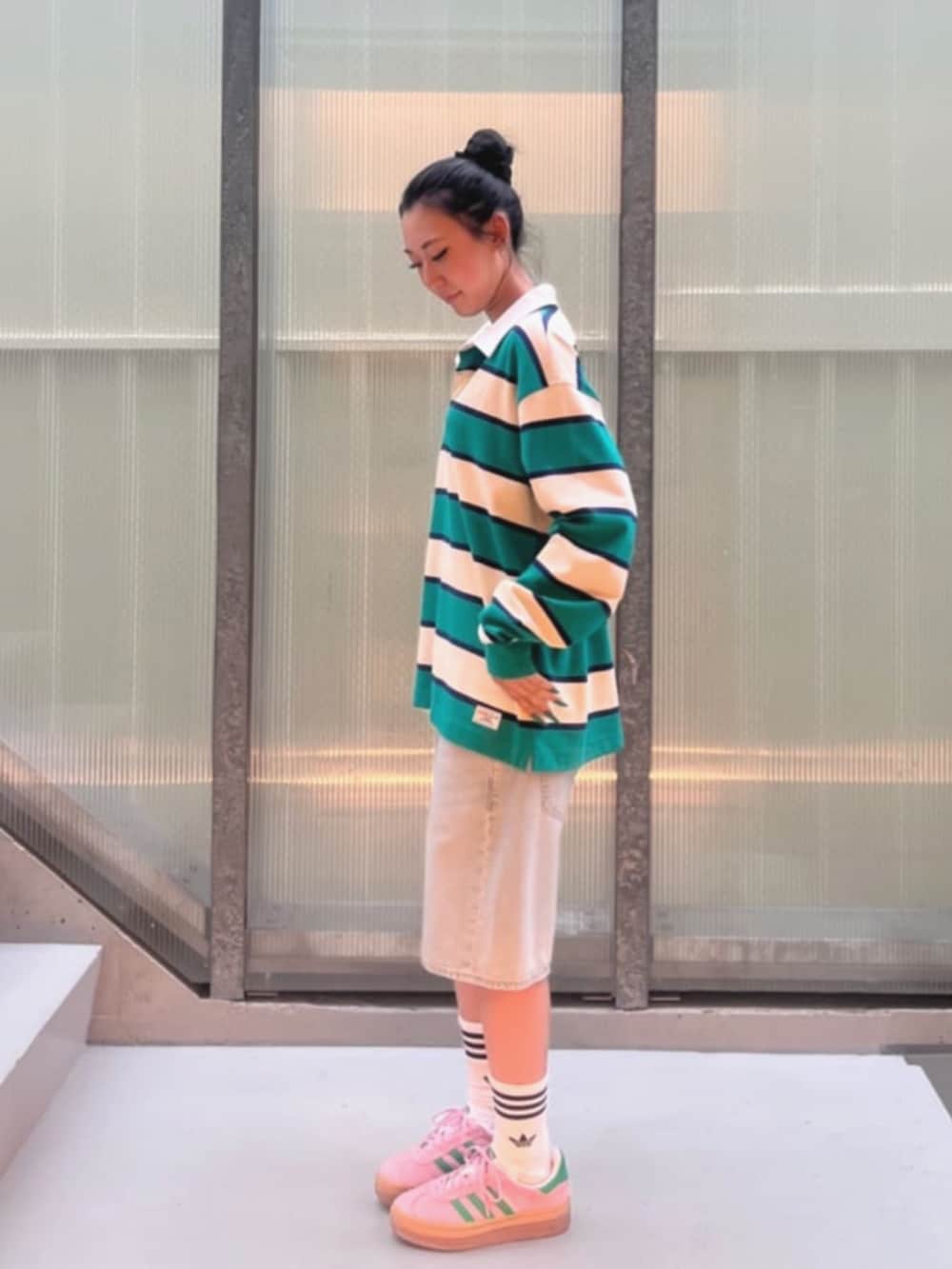 イエロー系のポロシャツ、ブルー系のデニムパンツを着用したレディースの秋コーディネートの3枚目の写真