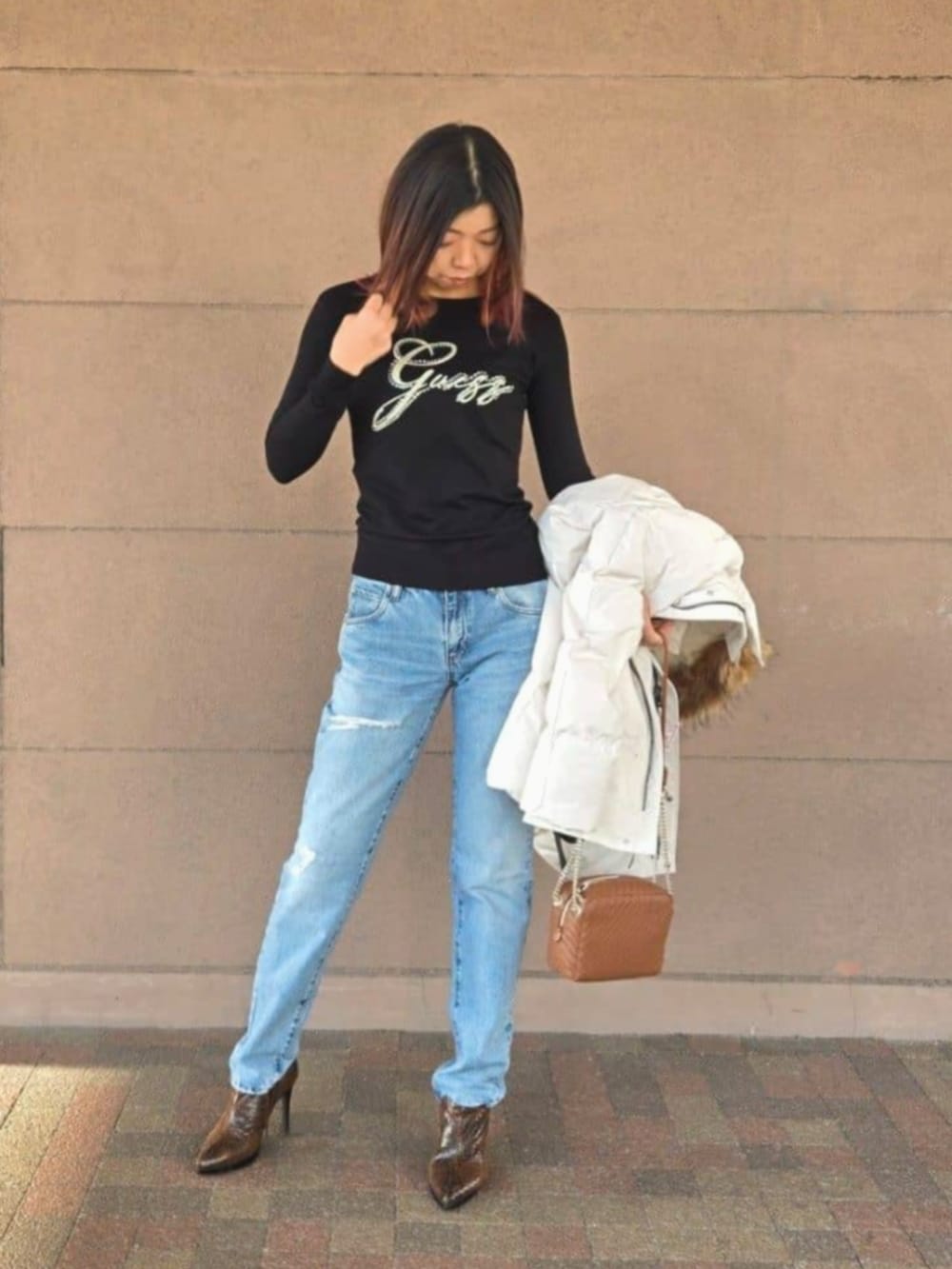 ブルー系のデニムパンツ、ブラック系のTシャツ/カットソー、ブラウン系のショルダーバッグを着用したレディースの冬コーディネートの4枚目の写真