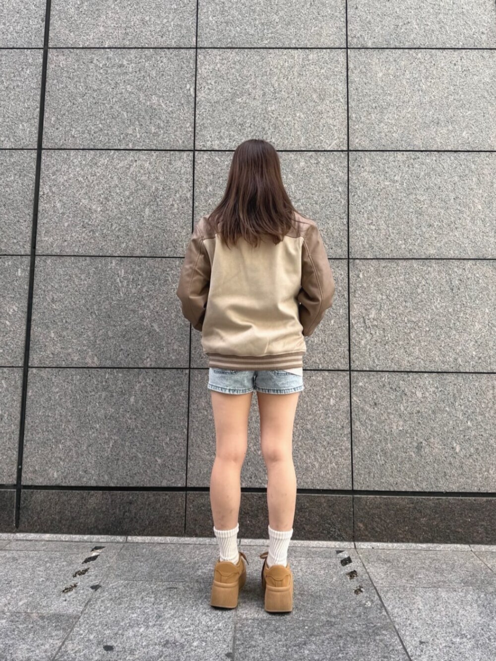 ブルー系のデニムパンツ、ベージュ系のTシャツ/カットソー、ベージュ系のスタジャンを着用したレディースの秋コーディネートの2枚目の写真