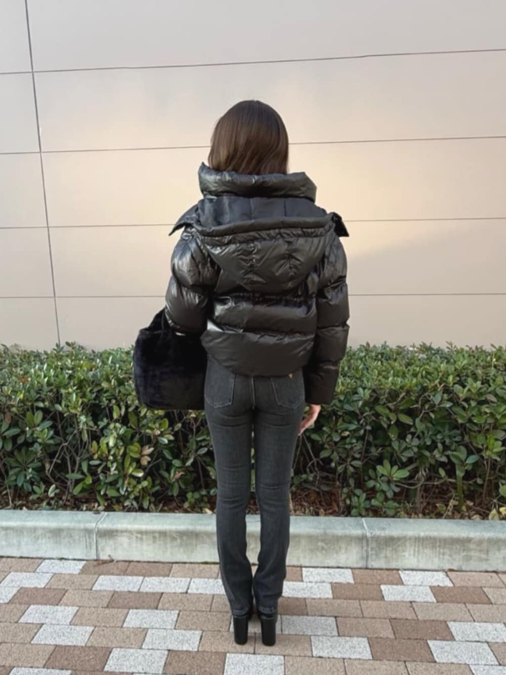 ブラック系のダウンジャケット/コート、ブラック系のショルダーバッグ、グレー系のTシャツ/カットソーを着用したレディースの冬コーディネートの2枚目の写真