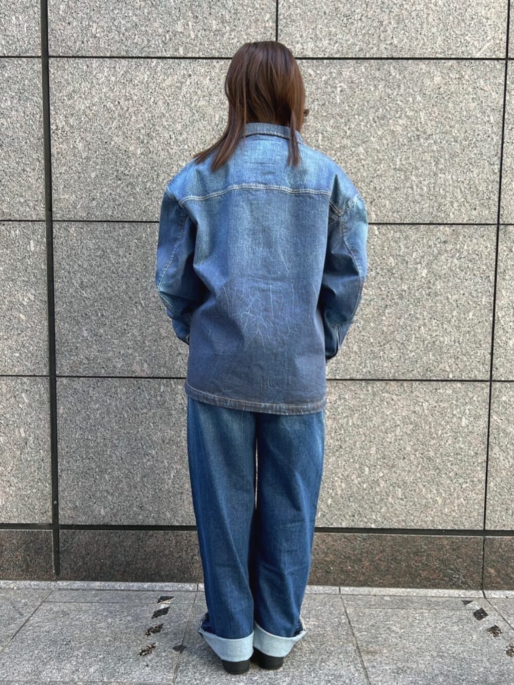 ブルー系のデニムパンツ、ブルー系のデニムジャケット、ブラック系のニット/セーターを着用したレディースの秋コーディネートの2枚目の写真