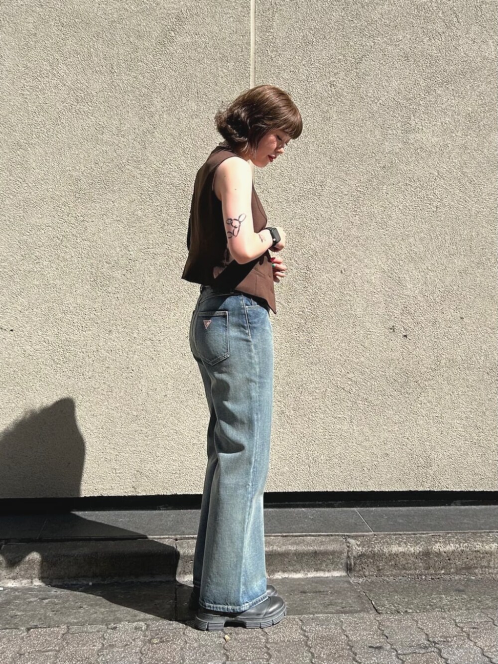 ブラウン系のベスト、ブルー系のデニムパンツ、ブラック系のハンドバッグを着用したレディースの夏コーディネートの3枚目の写真