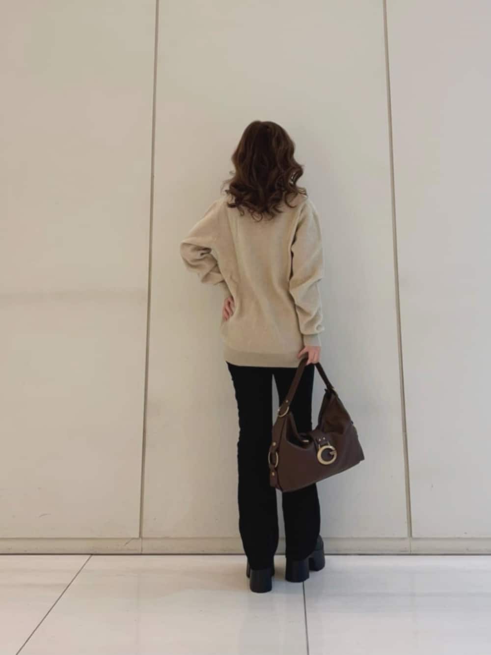 ブラック系のデニムパンツ、ブラウン系のショルダーバッグ、ベージュ系のニット/セーターを着用したレディースの冬コーディネートの2枚目の写真