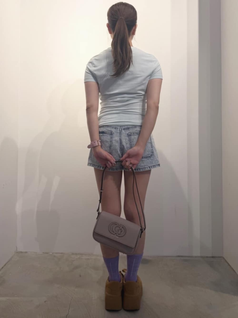 ブルー系のデニムパンツ、グリーン系のTシャツ/カットソー、ベージュ系のショルダーバッグを着用したレディースの冬コーディネートの2枚目の写真