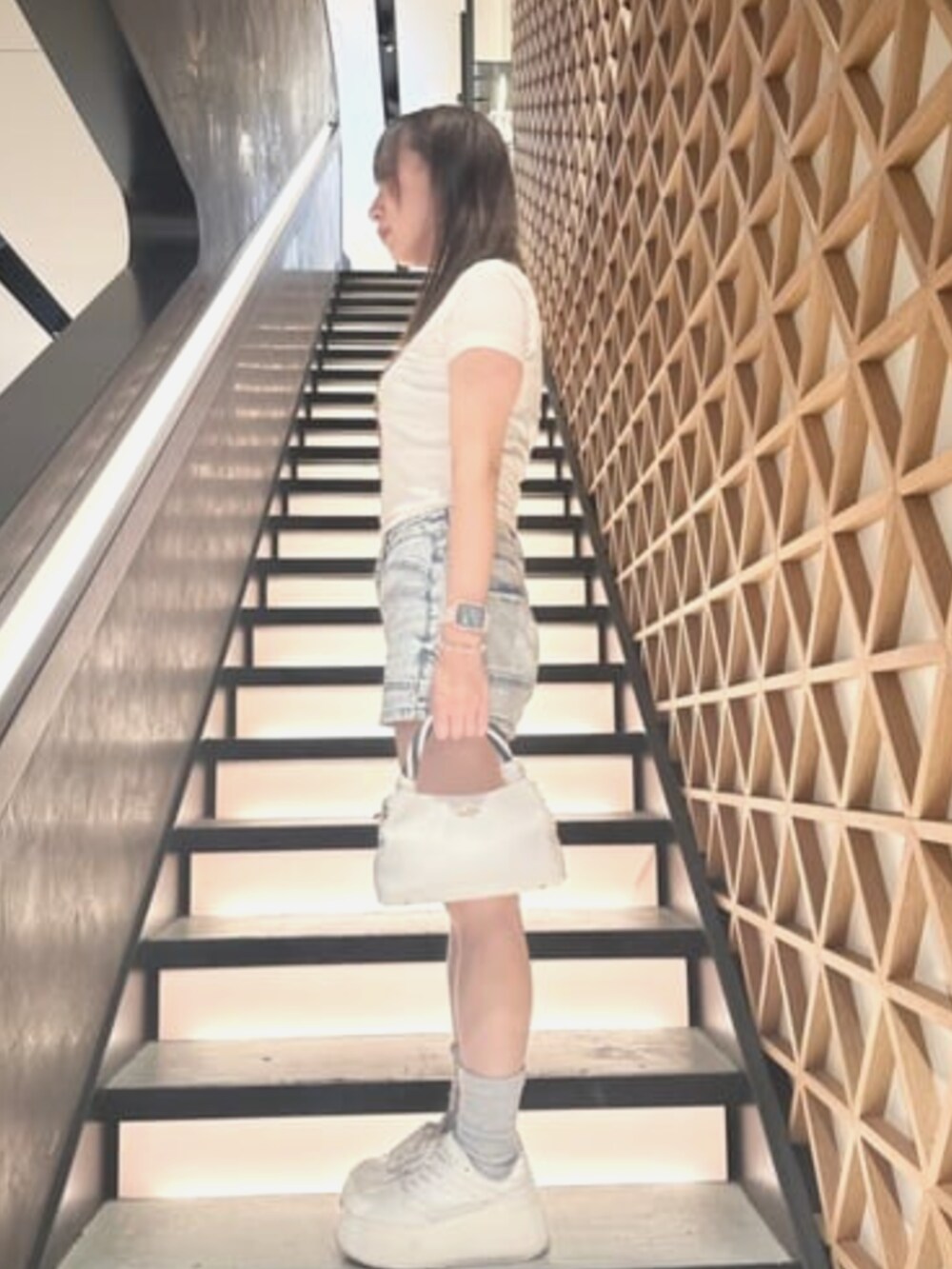 ベージュ系のTシャツ/カットソー、ブルー系のデニムパンツ、ホワイト系のショルダーバッグを着用したレディースの夏コーディネートの3枚目の写真