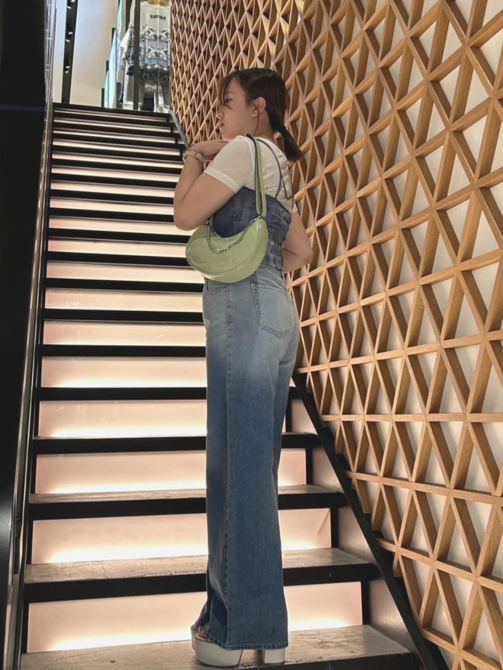 ホワイト系のその他トップス、グリーン系のハンドバッグ、ブルー系のデニムパンツを着用したレディースの夏コーディネートの3枚目の写真