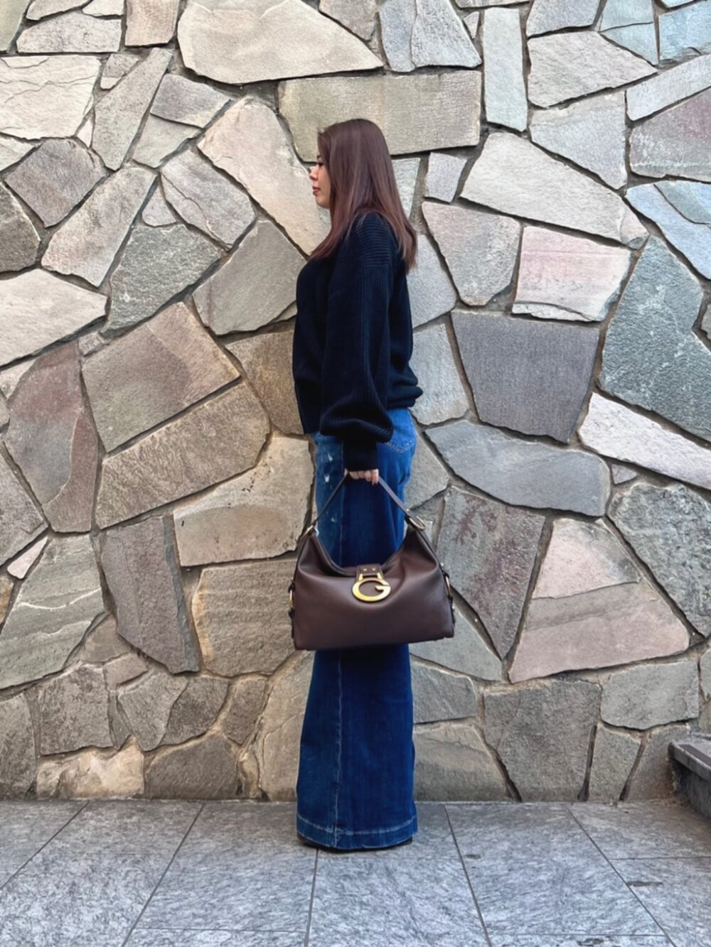 ブルー系のデニムパンツ、ホワイト系のニット/セーター、ブラウン系のショルダーバッグを着用したレディースの秋コーディネートの3枚目の写真