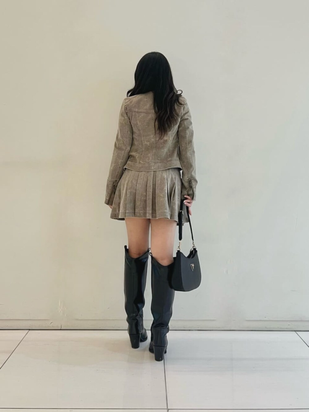 ブラック系のショルダーバッグ、ホワイト系のニット/セーター、ベージュ系のスカートを着用したレディースの秋コーディネートの2枚目の写真