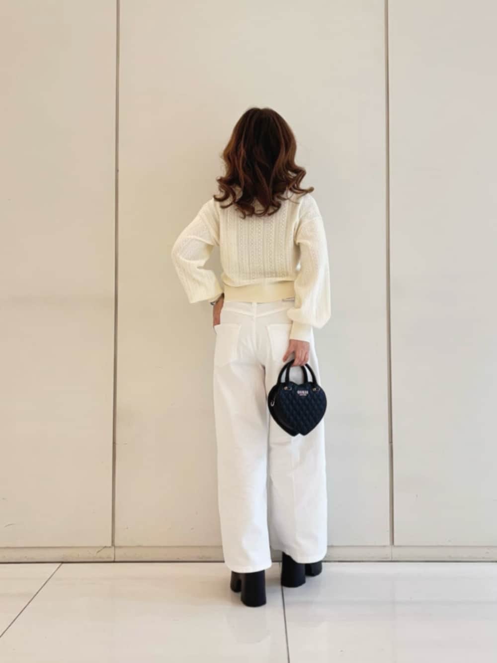ホワイト系のデニムパンツ、ブラック系のショルダーバッグ、ベージュ系のカーディガン/ボレロを着用したレディースの冬コーディネートの2枚目の写真