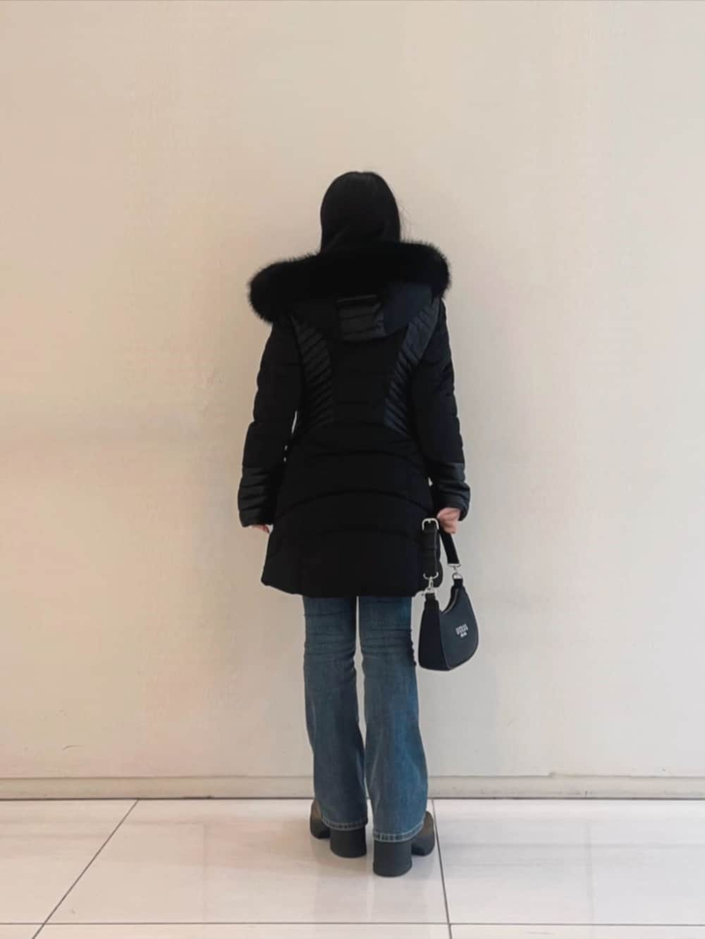 ブルー系のデニムパンツ、ホワイト系のニット/セーター、ブラック系のショルダーバッグを着用したレディースの冬コーディネートの2枚目の写真