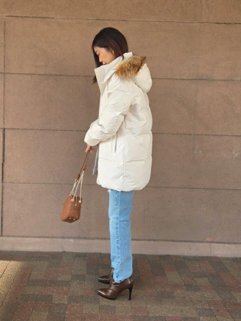 ブルー系のデニムパンツ、ブラック系のTシャツ/カットソー、ブラウン系のショルダーバッグを着用したレディースの冬コーディネートの3枚目の写真