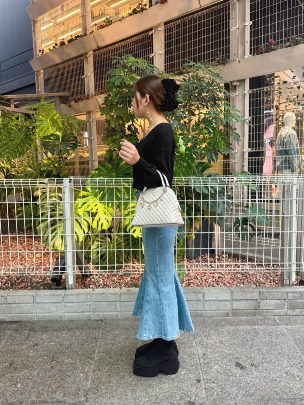 ブルー系のデニムスカート、ブラック系のカーディガン/ボレロ、ホワイト系のショルダーバッグを着用したレディースの秋コーディネートの3枚目の写真