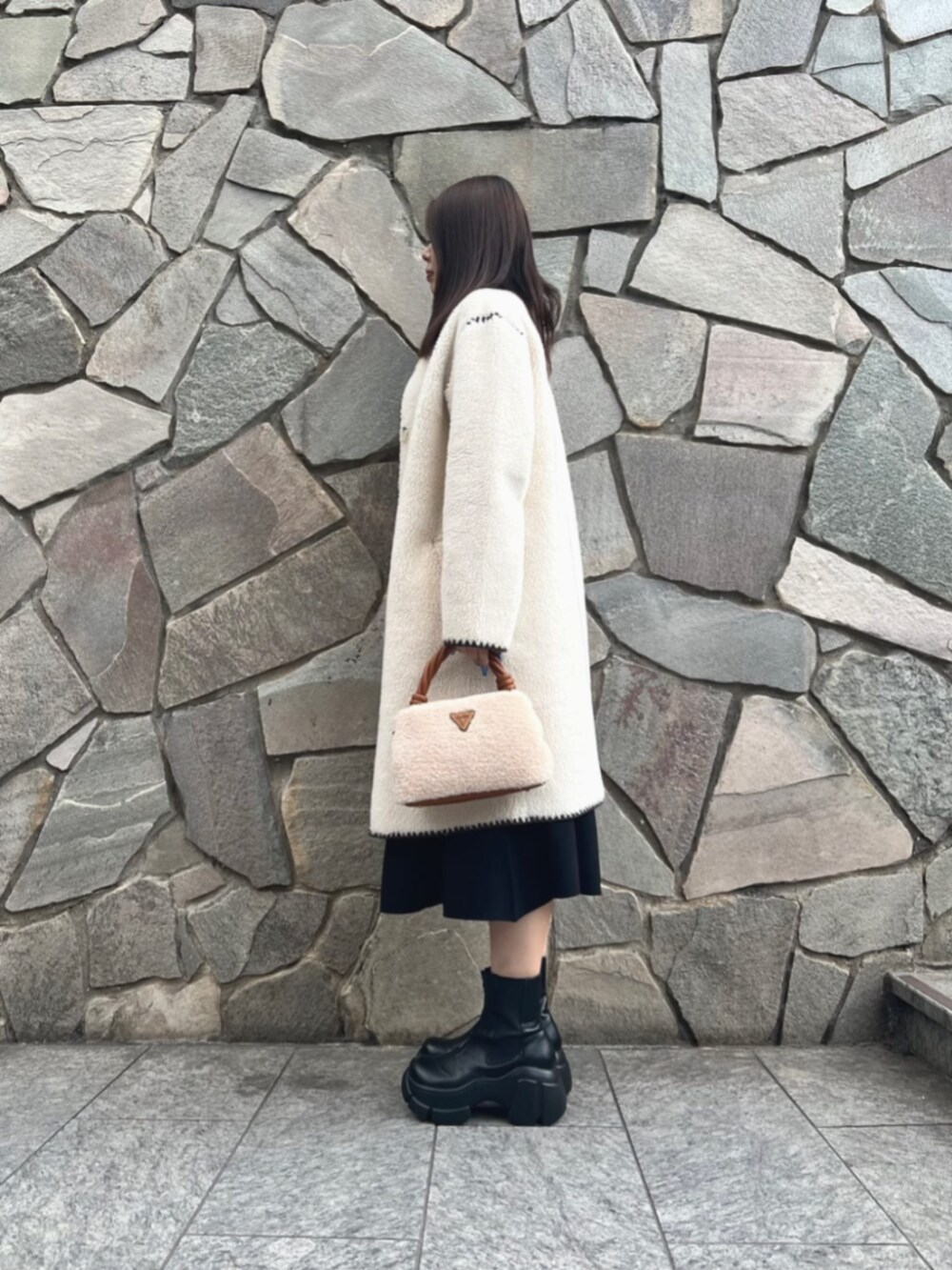 ブラック系のワンピース、ホワイト系のノーカラージャケット、イエロー系のショルダーバッグを着用したレディースの冬コーディネートの3枚目の写真