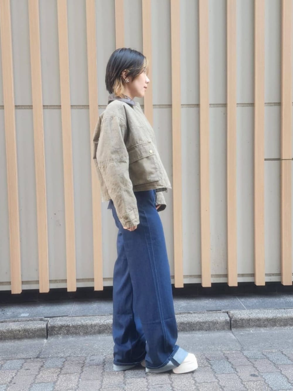 ホワイト系のTシャツ/カットソー、ブルー系のデニムパンツ、グリーン系のミリタリージャケットを着用したレディースの冬コーディネートの3枚目の写真