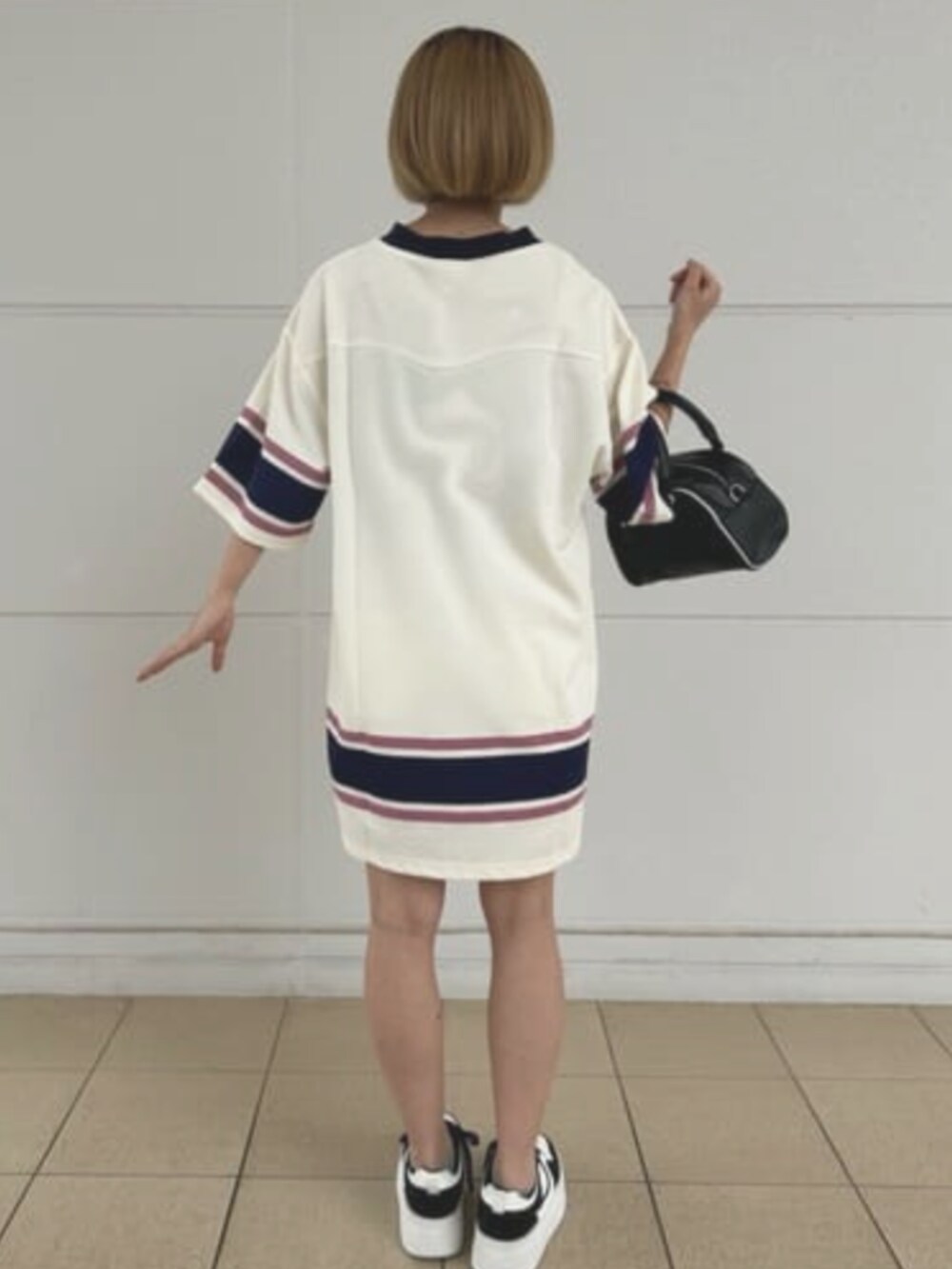 ブラック系のハンドバッグ、ホワイト系のワンピースを着用したレディースの夏コーディネートの2枚目の写真