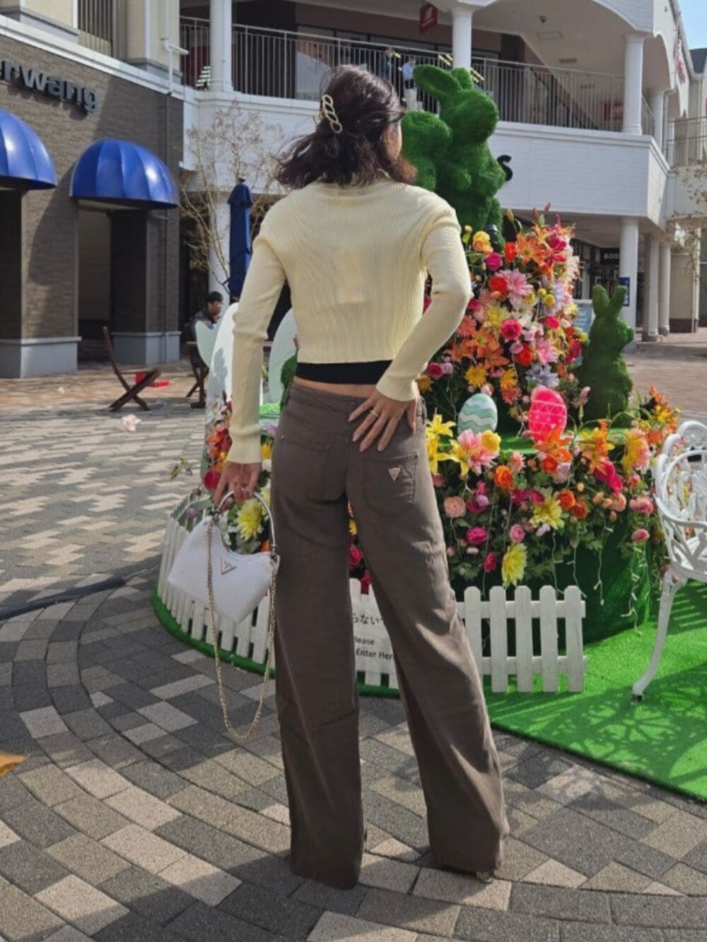 イエロー系のカーディガン/ボレロ、ホワイト系のハンドバッグ、ブラウン系のその他パンツを着用したレディースの夏コーディネートの2枚目の写真