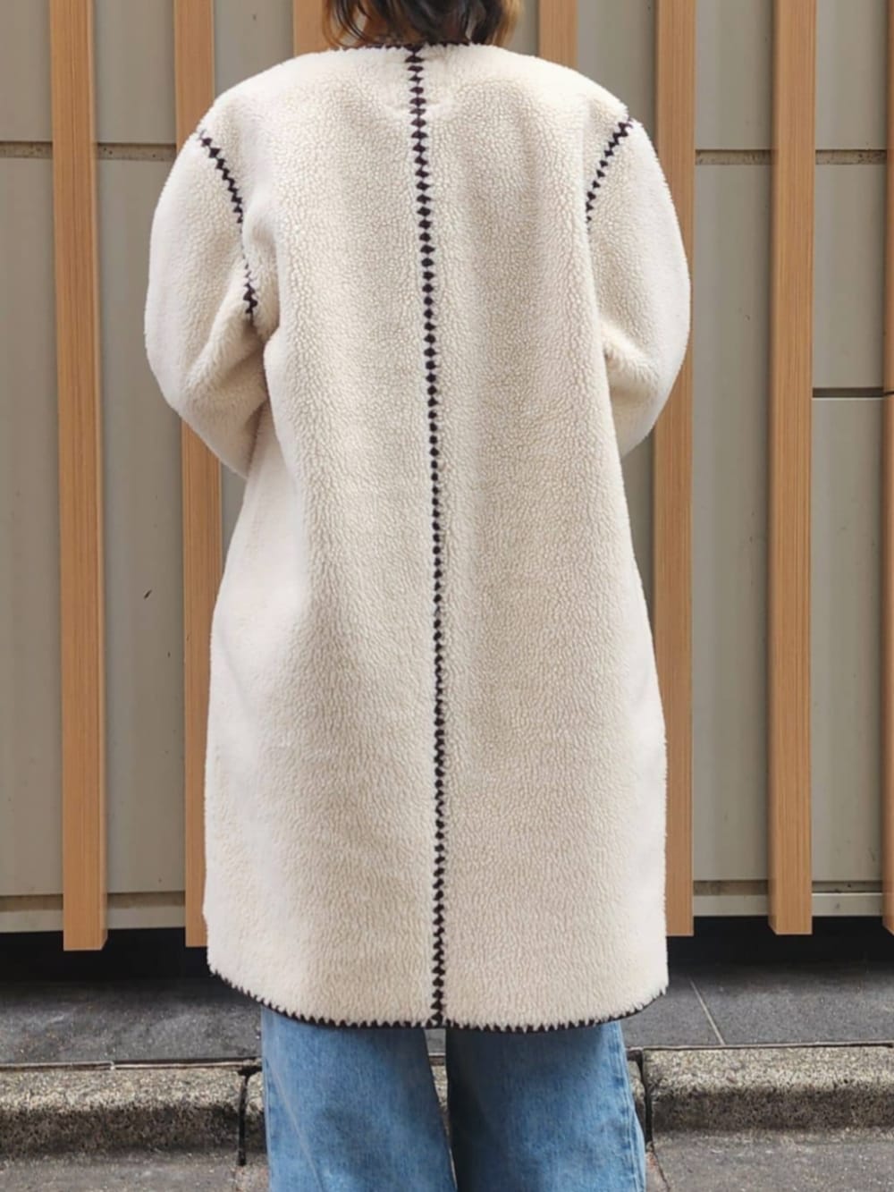 ホワイト系のタンクトップ、ブルー系のデニムパンツ、ホワイト系のノーカラージャケットを着用したレディースの冬コーディネートの2枚目の写真