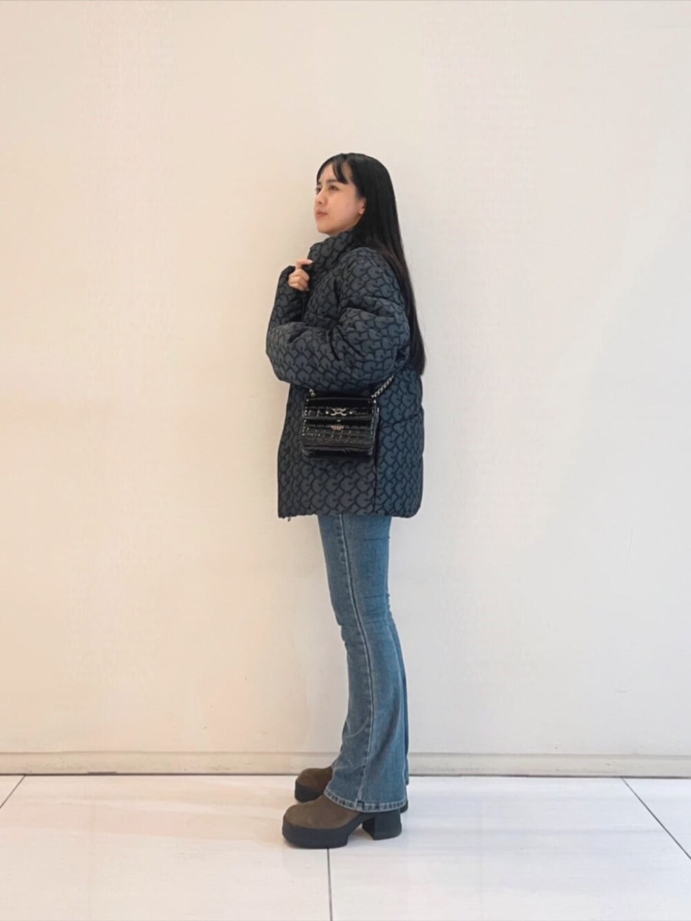 ブルー系のデニムパンツ、ブラック系のニット/セーター、ブラック系のショルダーバッグを着用したレディースの冬コーディネートの3枚目の写真