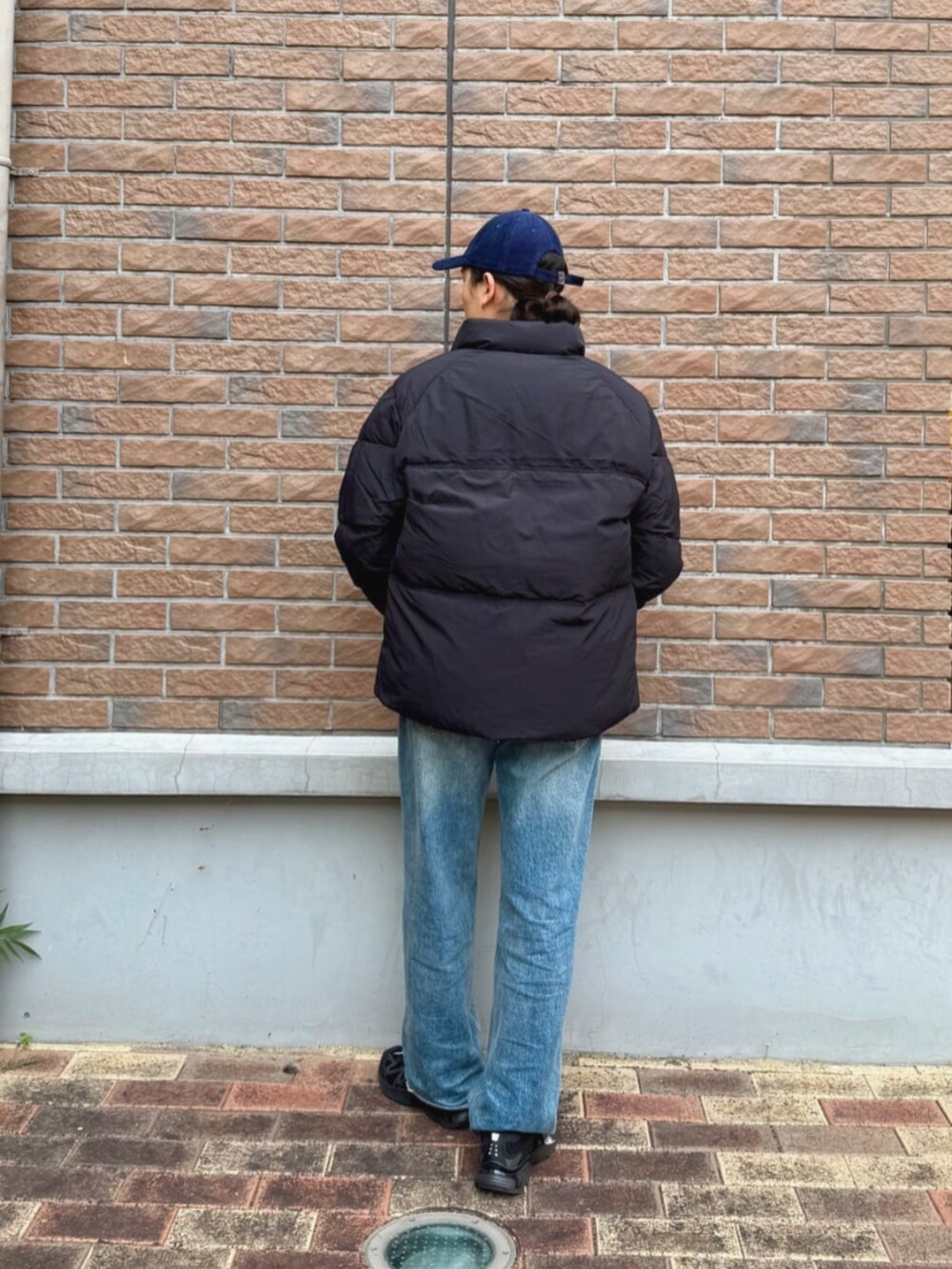 ブラック系のダウンジャケット/コート、ブルー系のキャップを着用したメンズの秋コーディネートの2枚目の写真