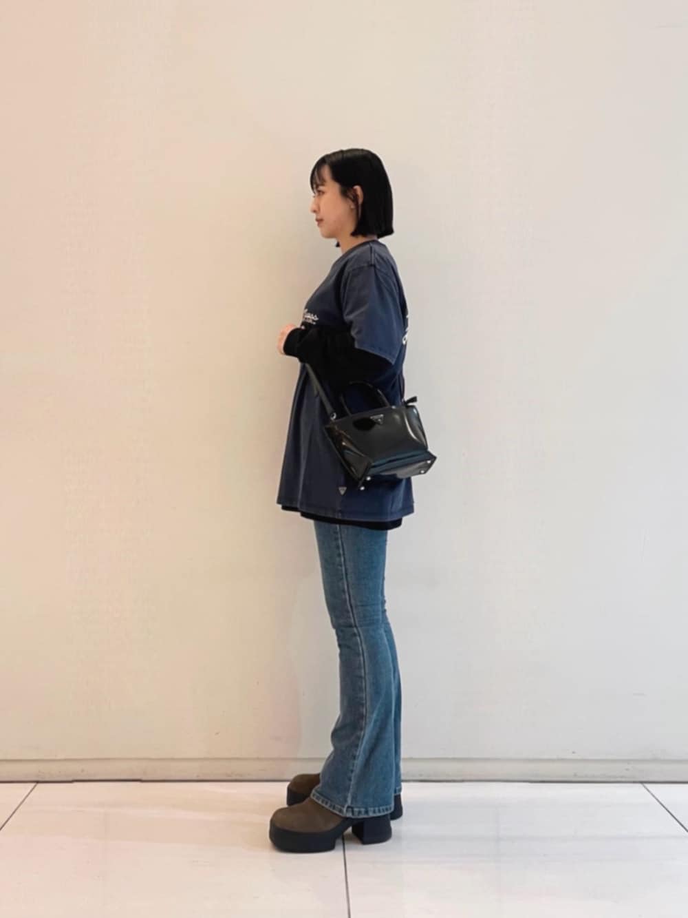 ブルー系のデニムパンツ、ブラック系のトートバッグ、ブラック系のTシャツ/カットソーを着用したレディースの冬コーディネートの3枚目の写真