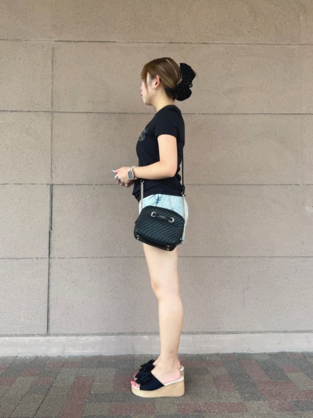 ブルー系のデニムパンツ、ブラック系のTシャツ/カットソー、ブラック系のショルダーバッグを着用したレディースの夏コーディネートの3枚目の写真