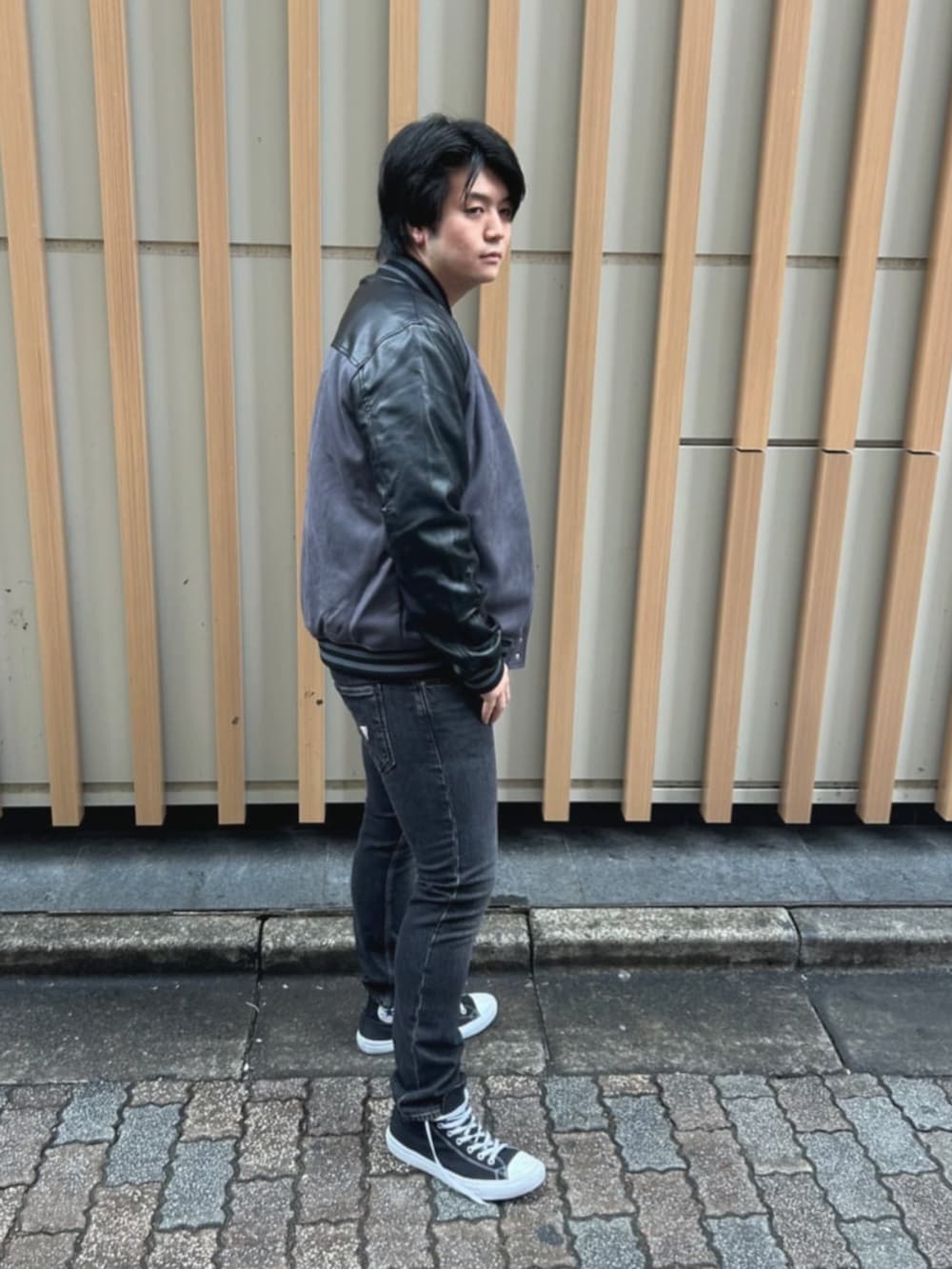 ベージュ系のTシャツ/カットソー、グレー系のスタジャン、グレー系のデニムパンツを着用したメンズの秋コーディネートの3枚目の写真