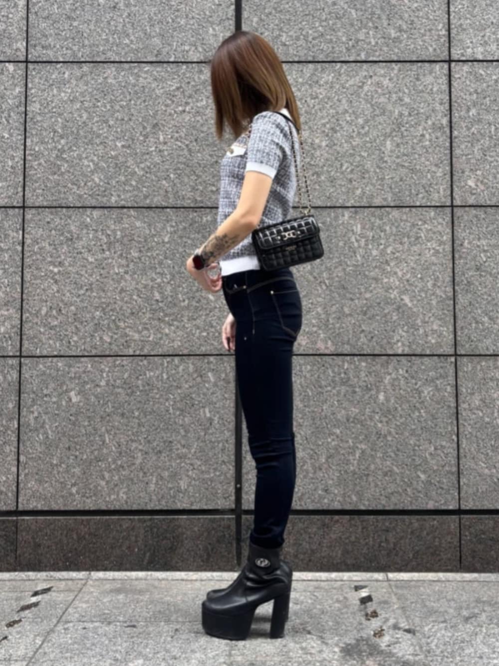 ブルー系のデニムパンツ、ブラック系のショルダーバッグ、ブラック系のニット/セーターを着用したレディースの春コーディネートの4枚目の写真