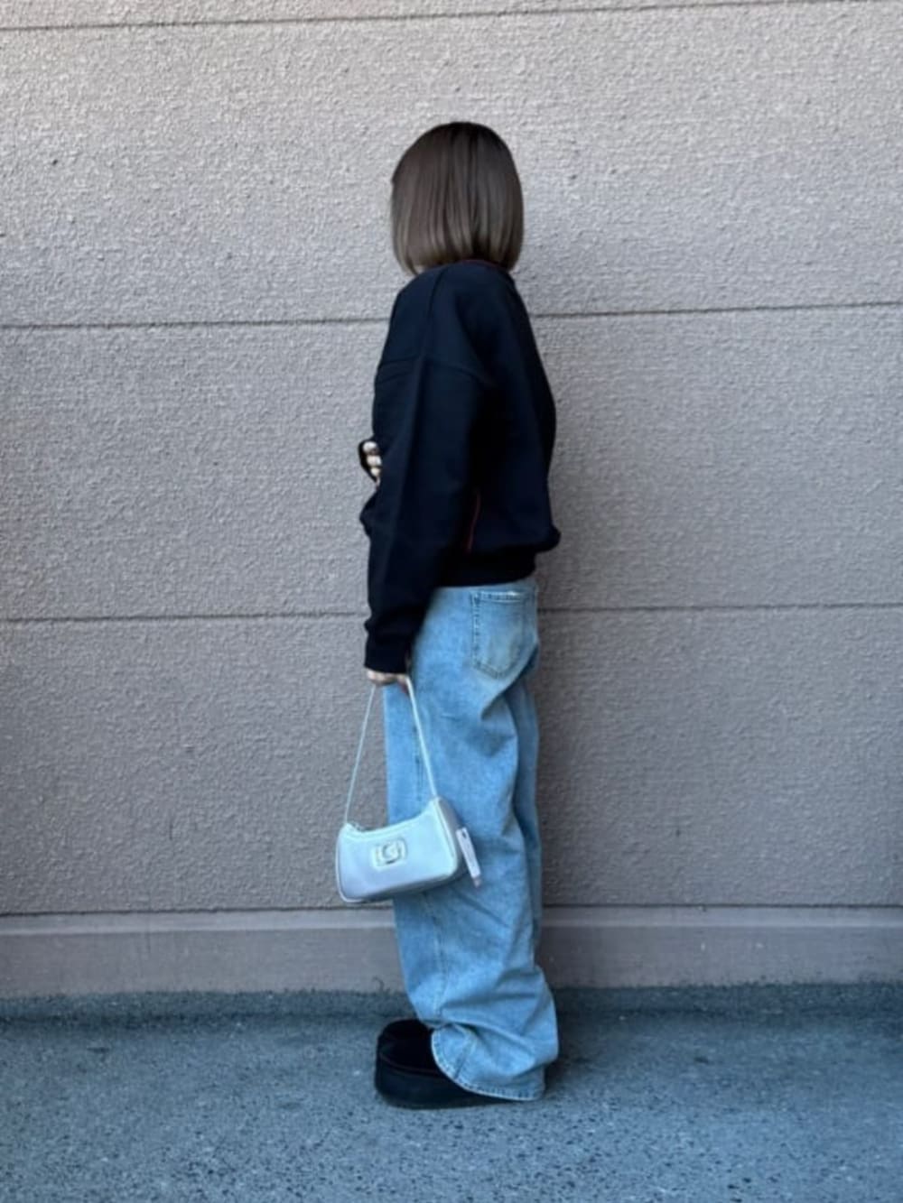 ブラック系のスウェット、ブルー系のデニムパンツを着用したレディースの春コーディネートの4枚目の写真