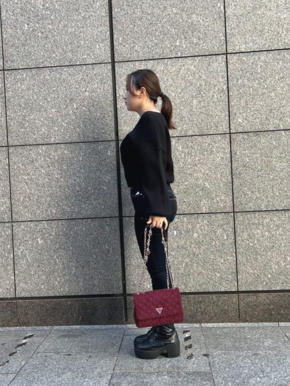 ブルー系のデニムパンツ、ブラック系のカーディガン/ボレロ、レッド系のショルダーバッグを着用したレディースの秋コーディネートの3枚目の写真