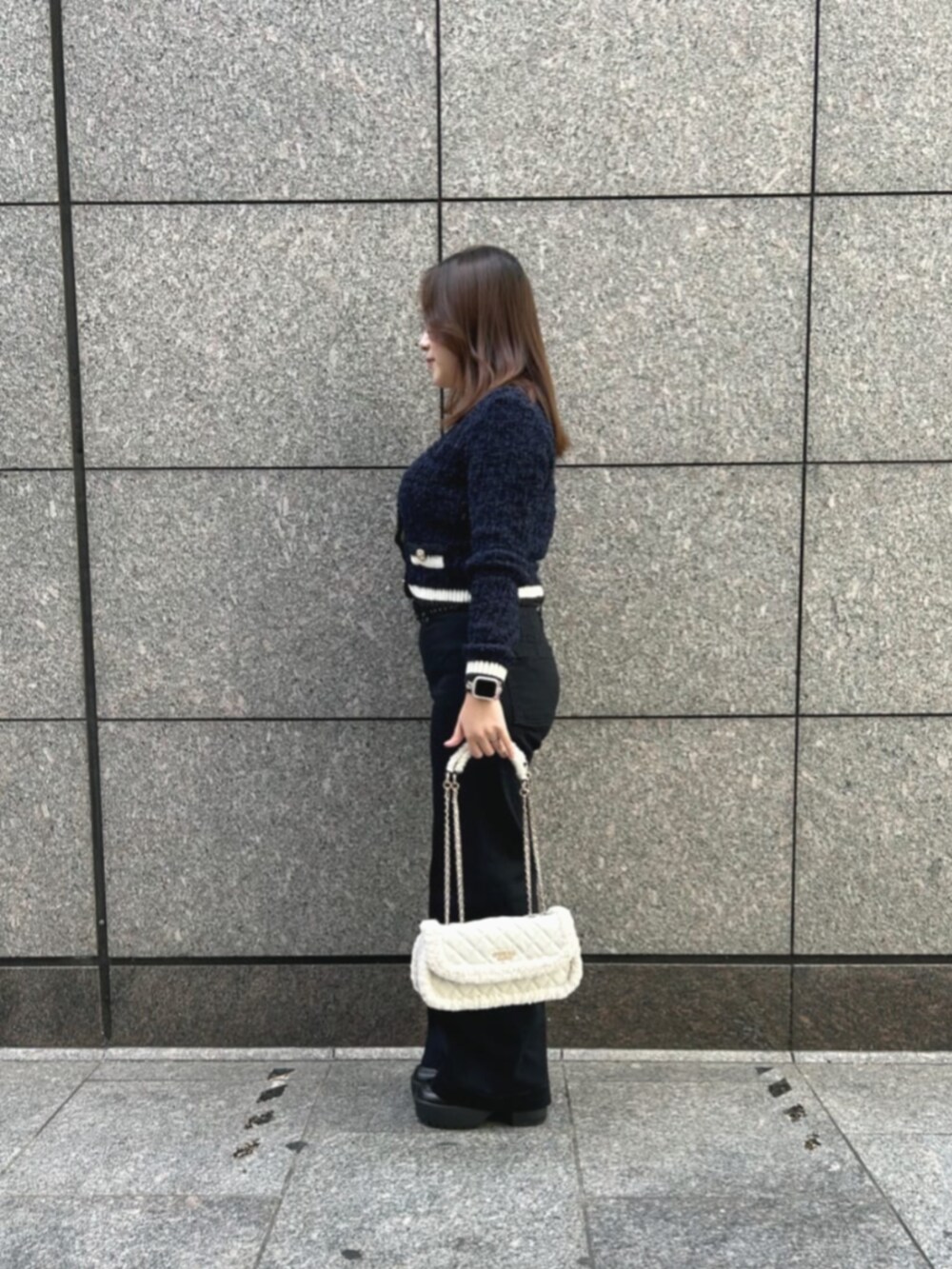 ブラック系のデニムパンツ、ブルー系のカーディガン/ボレロ、ホワイト系のショルダーバッグを着用したレディースの冬コーディネートの3枚目の写真
