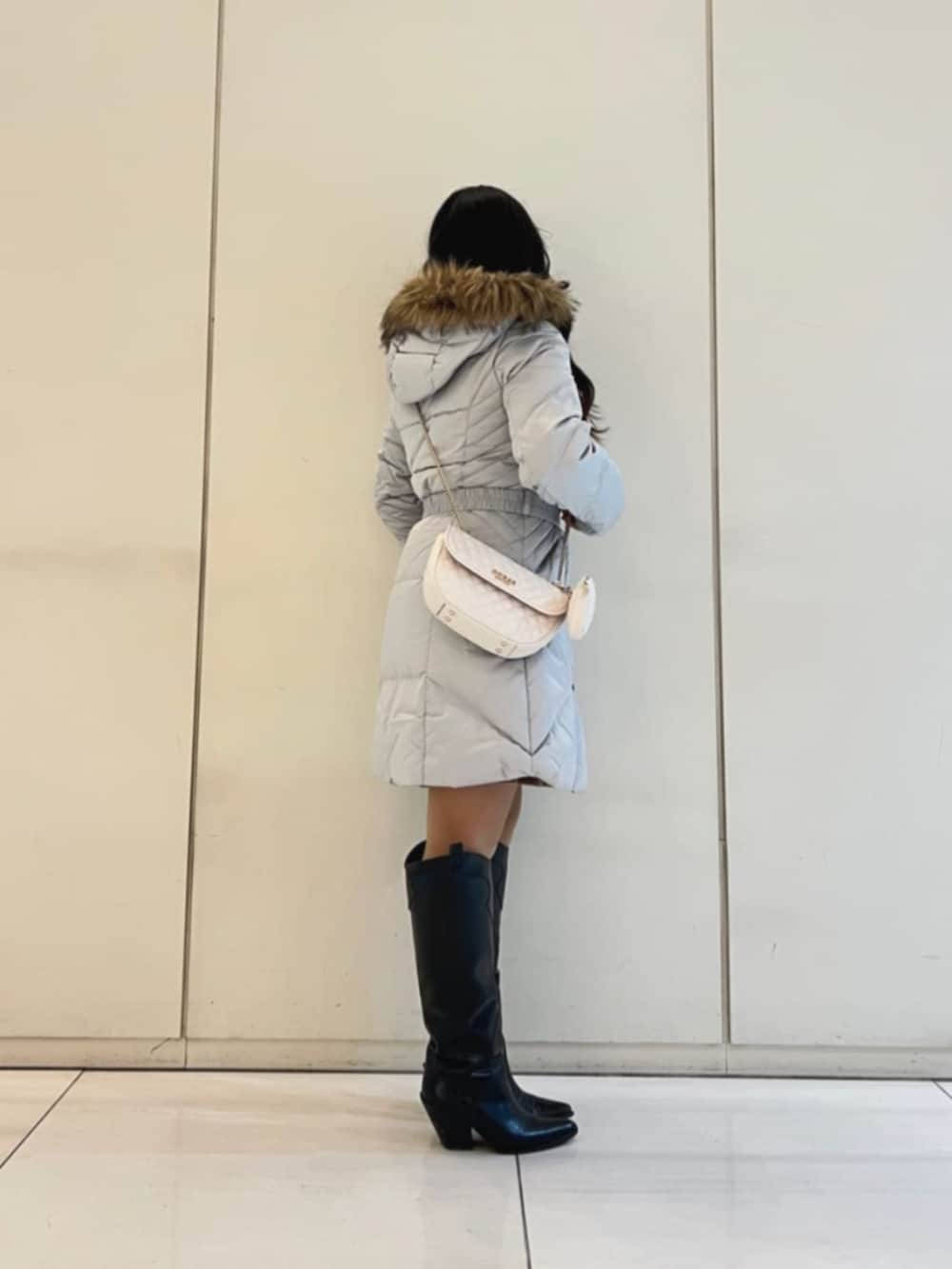 グレー系のダウンジャケット/コート、ベージュ系のワンピース、ホワイト系のショルダーバッグを着用したレディースの冬コーディネートの3枚目の写真