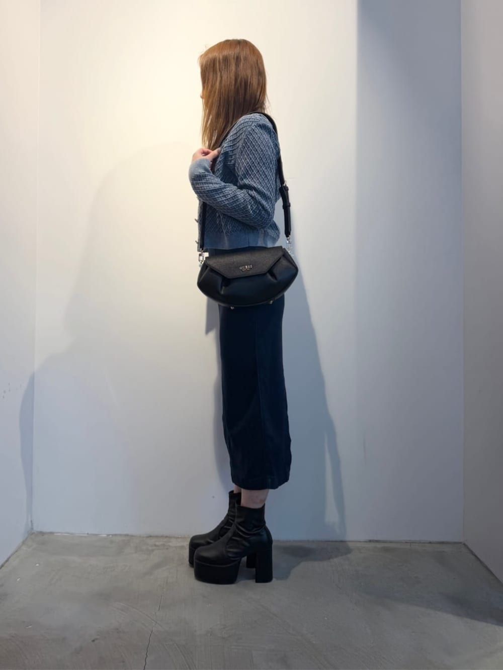 ブラック系のショルダーバッグ、ブルー系のワンピース、グレー系のニット/セーターを着用したレディースの冬コーディネートの3枚目の写真